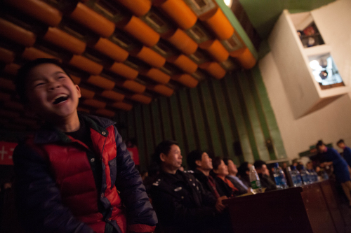 一名小观众兴致勃勃地看着台上老师们的精彩表演